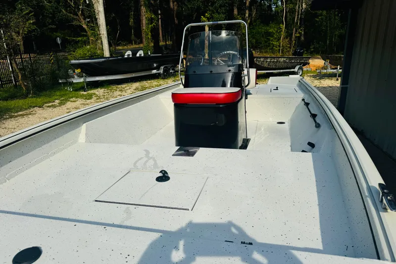 Slide: The Image of 2024 SeaArk Shadow 19 v boat with center console and red seat, parked outdoors. - 30