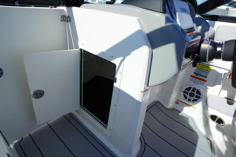 Slide: The Image of 2026 Chaparral 21 SSi OB boat interior with open storage compartment and control panel. - 26