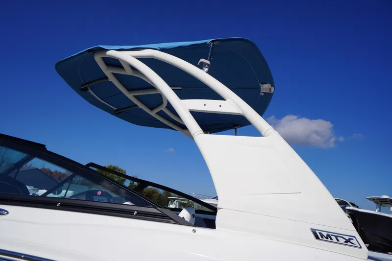 Slide: The Image of 2026 Chaparral 21 SSi OB boat with blue canopy against clear sky. - 29