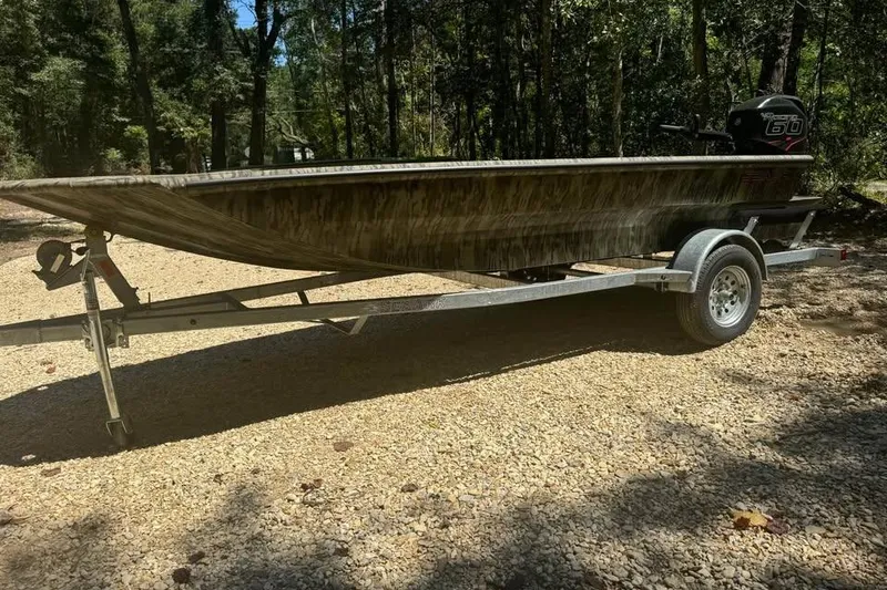 The Image of 2025 SeaArk 1752 Slayer Pro boat on trailer in wooded area. - 1
