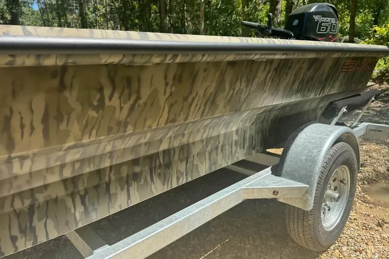 Slide: The Image of 2025 SeaArk 1752 Slayer Pro boat with camouflage design on a trailer. - 4
