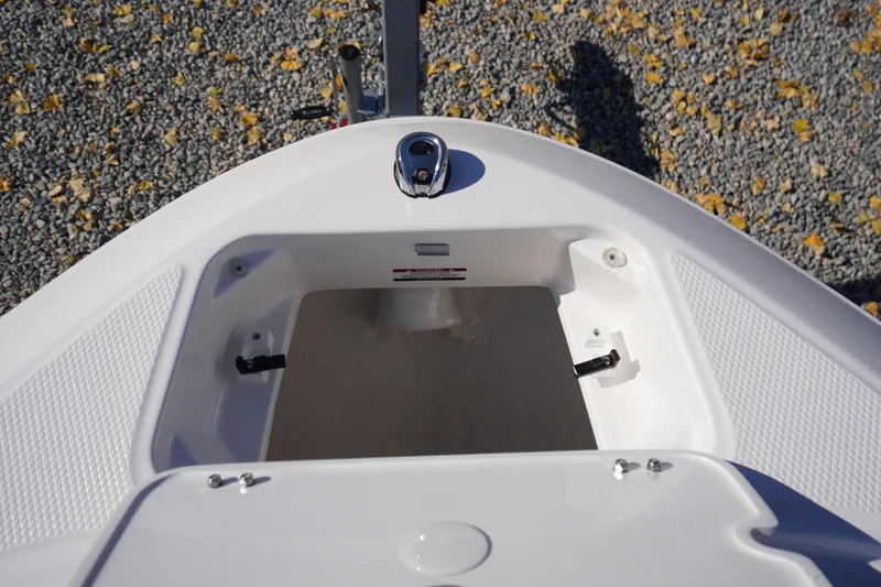 Slide: The Image of 2026 Chaparral 21 SSi OB boat bow storage compartment, open on gravel surface. - 5