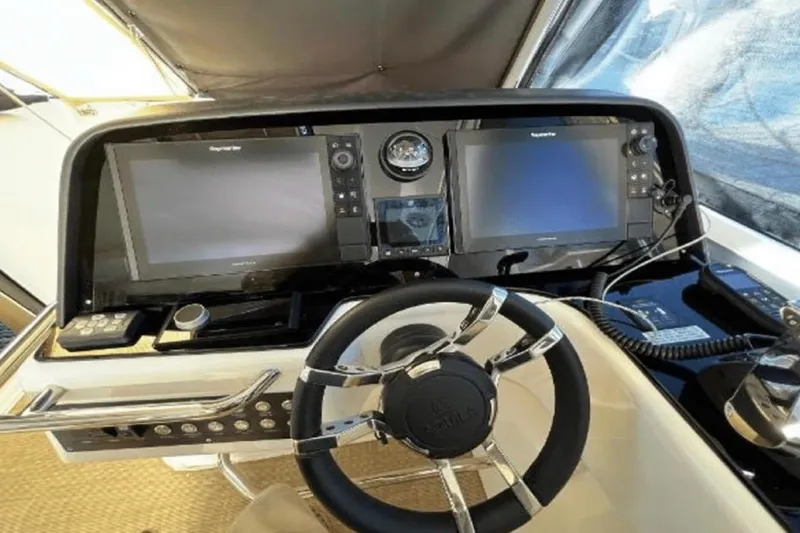 Slide: The Image of Helm of 2022 Aquila 36 Cruiser with dual navigation screens and modern controls. - 18