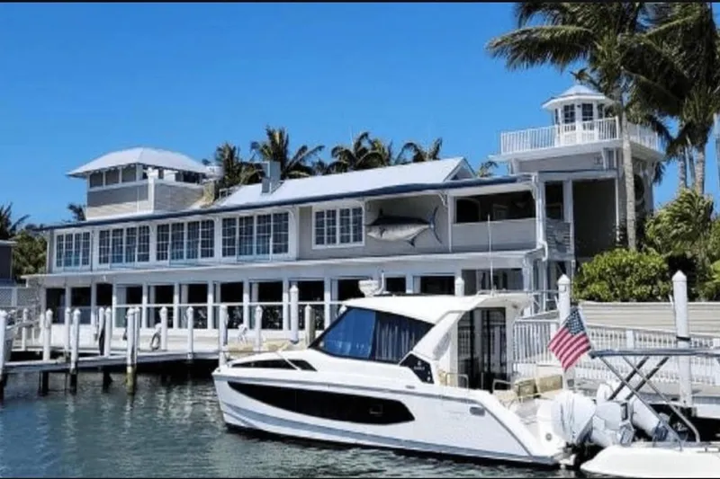 Slide: The Image of Aquila 36 Cruiser 2022 docked by a waterfront house with palm trees. - 7