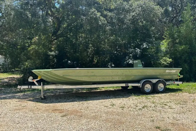 The Image of 2026 SeaArk 2672 MV boat on trailer, parked outdoors with trees in background. - 1