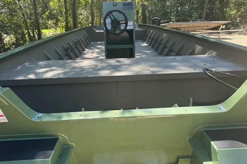 Slide: The Image of 2026 SeaArk 2672 MV boat interior with steering console, surrounded by trees. - 10