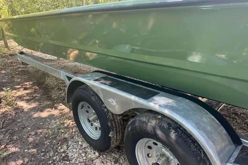 Slide: The Image of 2026 SeaArk 2672 MV boat on trailer, green hull, parked on gravel. - 12