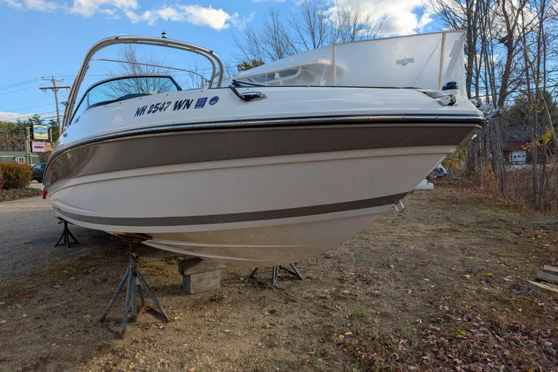 The Image of 2018 Rinker QX23 BR boat on stands, outdoors, under a clear sky. - 0