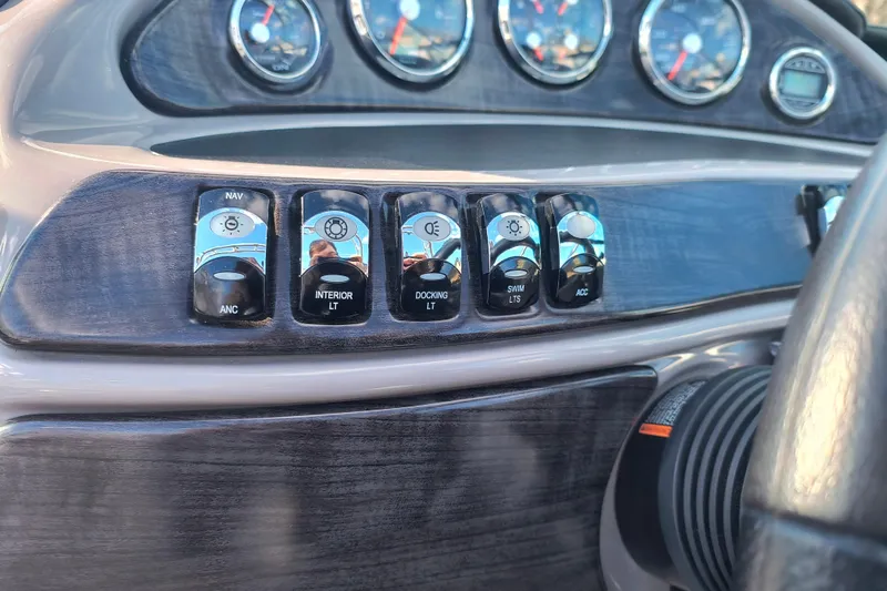 Slide: The Image of Dashboard controls of a 2018 Rinker QX23 BR boat, featuring various light switches. - 13