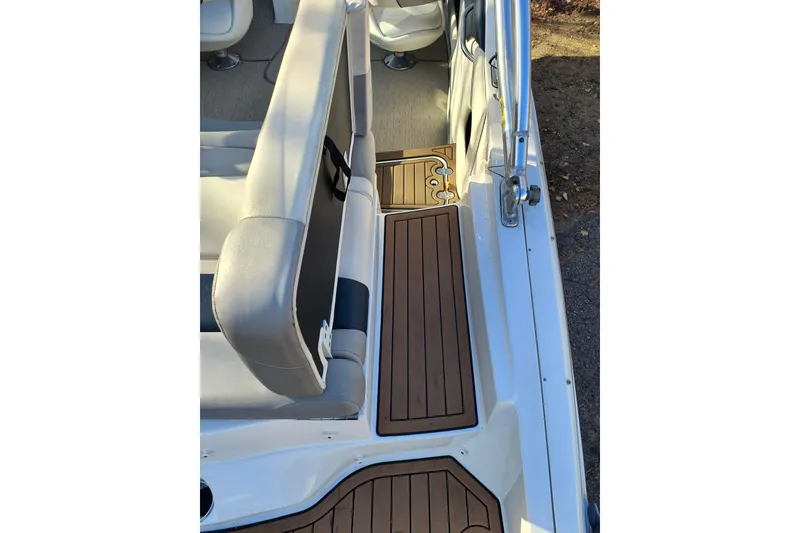 Slide: The Image of 2018 Rinker QX23 BR boat interior with cushioned seating and wood-style flooring. - 26