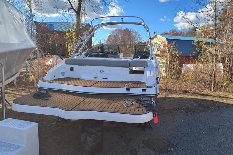 Slide: The Image of 2018 Rinker QX23 BR boat with teak deck, parked outdoors under blue sky. - 28