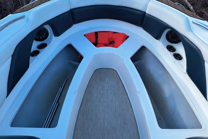 Slide: The Image of 2018 Rinker QX23 BR boat interior with seating, cup holders, and storage compartments. - 8