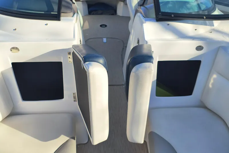 Slide: The Image of 2018 Rinker QX23 BR boat interior with open storage compartments and cushioned seating. - 9