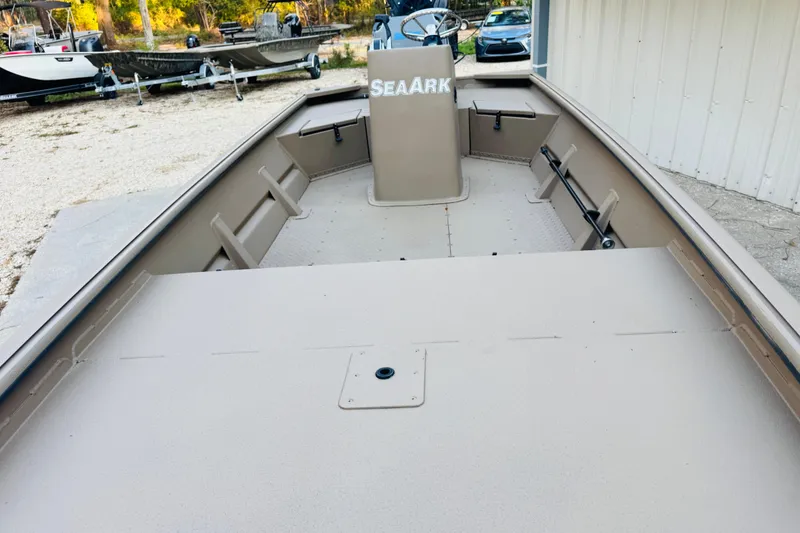 Slide: The Image of 2025 SeaArk Mud Runner 180 boat, beige interior, parked outdoors near other boats. - 22