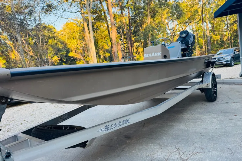 Slide: The Image of 2025 SeaArk Mud Runner 180 boat on trailer, surrounded by trees and parked cars. - 24