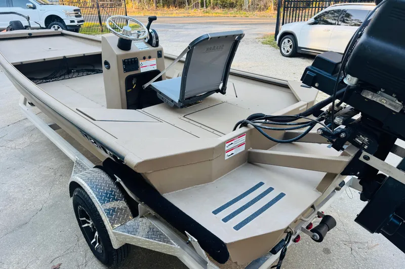 Slide: The Image of 2025 SeaArk Mud Runner 180 boat on trailer, featuring steering console and outboard motor. - 28