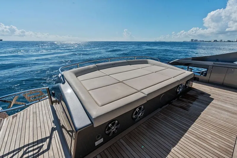 Slide: The Image of 2019 Pershing 9X yacht deck with sunbed, overlooking the ocean under a clear blue sky. - 32