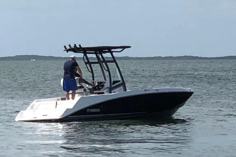 The Image of 2019 Yamaha Boats 210 FSH on calm water with a person onboard. - 1