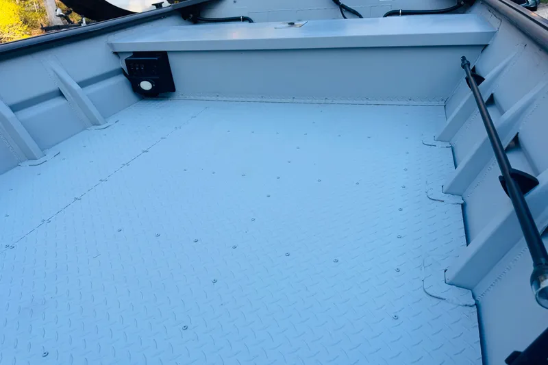 Slide: The Image of 2025 SeaArk 1660 MVT boat interior with diamond plate flooring and side storage compartments. - 12