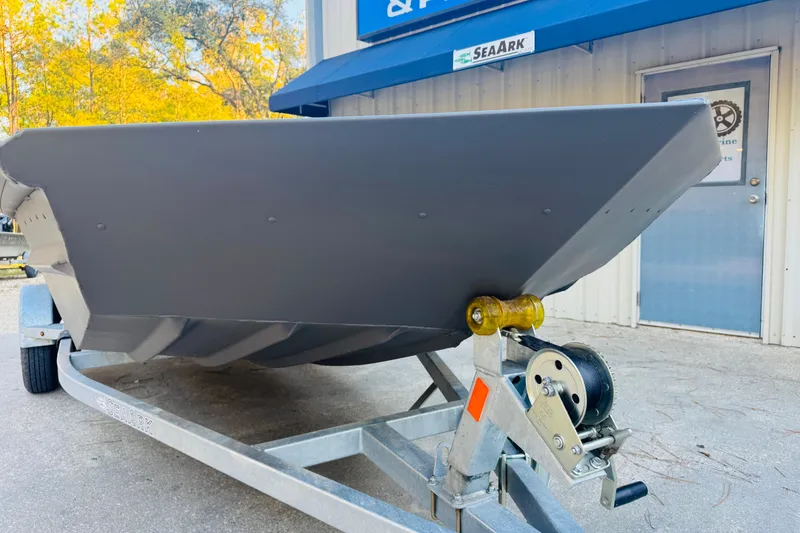 Slide: The Image of 2025 SeaArk 1660 MVT boat on trailer, parked outside a building with autumn trees. - 13