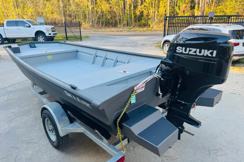 Slide: The Image of 2025 SeaArk 1660 MVT boat with Suzuki outboard motor on trailer, parked outdoors. - 17