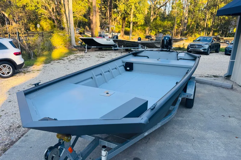 Slide: The Image of 2025 SeaArk 1660 MVT boat on trailer, parked outdoors with trees in background. - 3