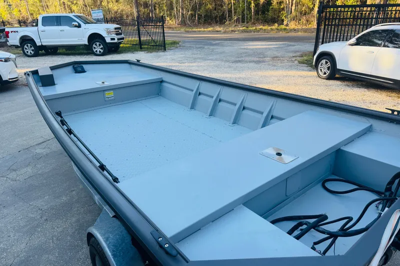 Slide: The Image of 2025 SeaArk 1660 MVT boat, spacious interior, parked outdoors near vehicles. - 5