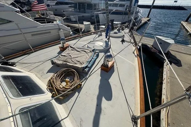 Slide: The Image of 1973 Maple Leaf Center Cockpit sailboat docked at marina with coiled rope and covered equipment. - 24