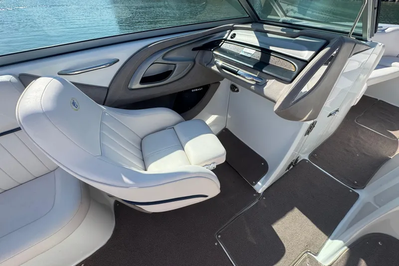 Slide: The Image of 2006 Cobalt 272 boat interior with white seating and dashboard, near water. - 18