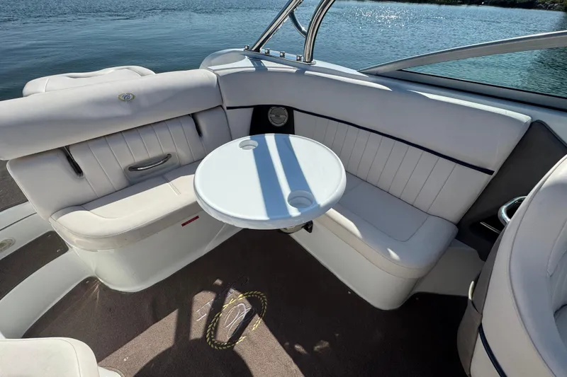 Slide: The Image of 2006 Cobalt 272 boat interior with white seating and round table on a sunny day. - 19