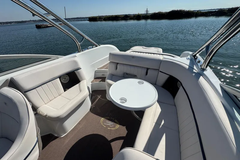 Slide: The Image of 2006 Cobalt 272 boat interior with white seating and round table on calm water. - 20