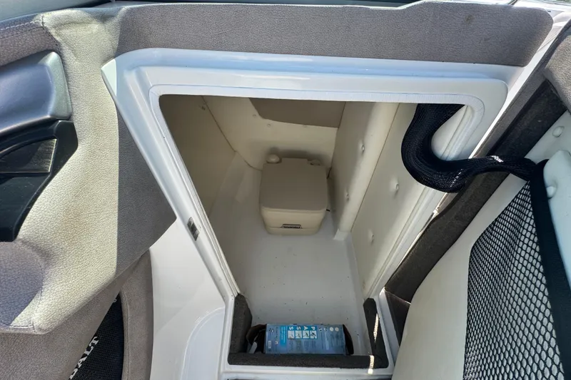Slide: The Image of Storage compartment in a 2006 Cobalt 272 boat, featuring a portable toilet and a water bottle. - 25