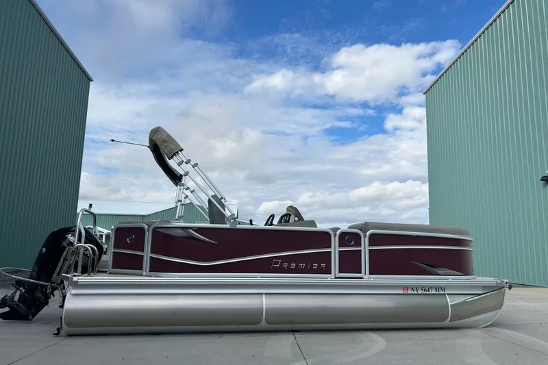 The Image of 2017 Premier 220 SunSation pontoon boat parked between green buildings under a cloudy sky. - 0