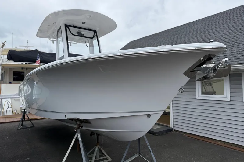 Slide: The Image of 2026 Sea Hunt Ultra 245 SE boat on stands, displayed outdoors near a building. - 4