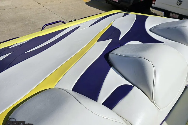 Slide: The Image of 2005 Baja 25 Outlaw boat interior with vibrant yellow, white, and blue upholstery design. - 107