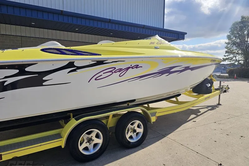 Slide: The Image of 2005 Baja 25 Outlaw speedboat on trailer, featuring vibrant yellow and purple graphics. - 12