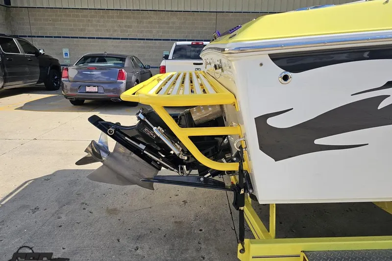 Slide: The Image of 2005 Baja 25 Outlaw boat with yellow accents parked near vehicles. - 14