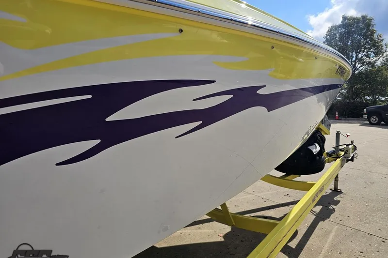 Slide: The Image of 2005 Baja 25 Outlaw boat with vibrant yellow and purple graphics on a trailer. - 21