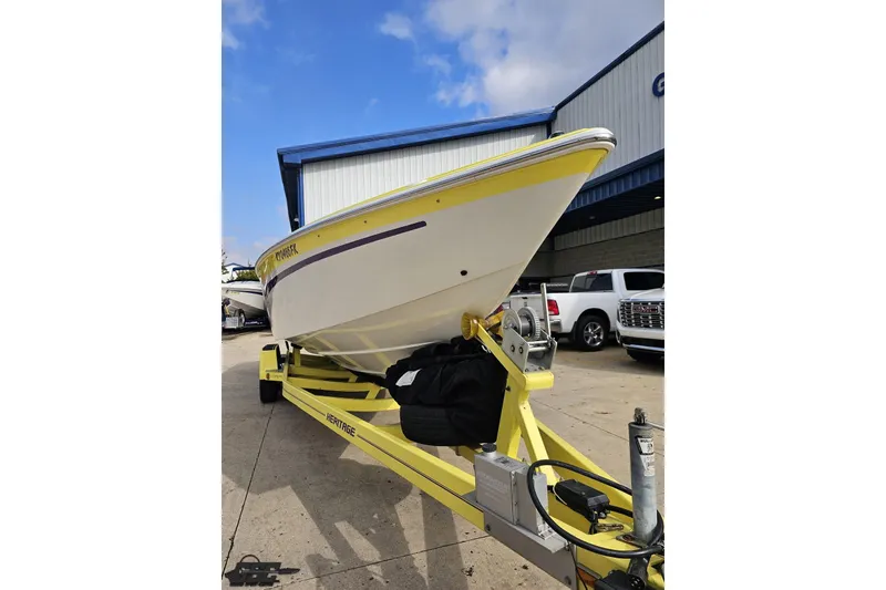 Slide: The Image of 2005 Baja 25 Outlaw boat on yellow trailer, parked outdoors under blue sky. - 23