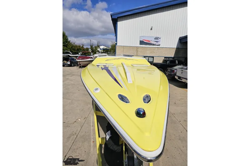 Slide: The Image of Yellow 2005 Baja 25 Outlaw boat parked outdoors under a cloudy sky. - 25