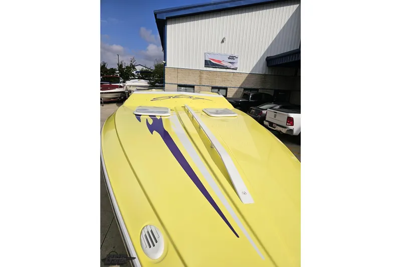 Slide: The Image of Yellow 2005 Baja 25 Outlaw boat with purple graphics, parked outside a building. - 26