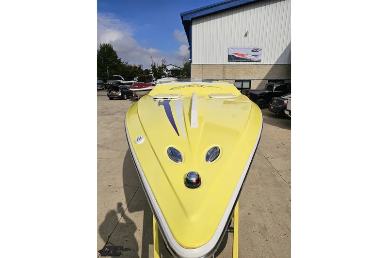 Slide: The Image of Yellow 2005 Baja 25 Outlaw boat parked outside a building on a sunny day. - 27