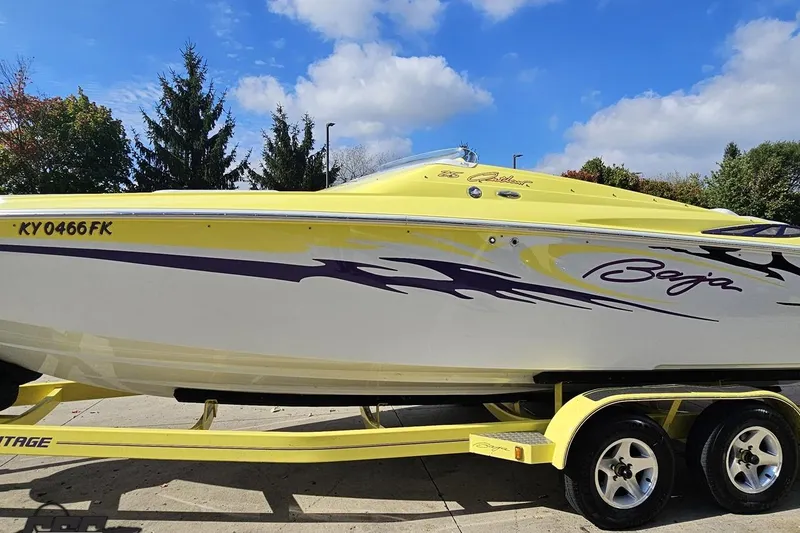 Slide: The Image of 2005 Baja 25 Outlaw speedboat with vibrant yellow and purple design on trailer. - 32
