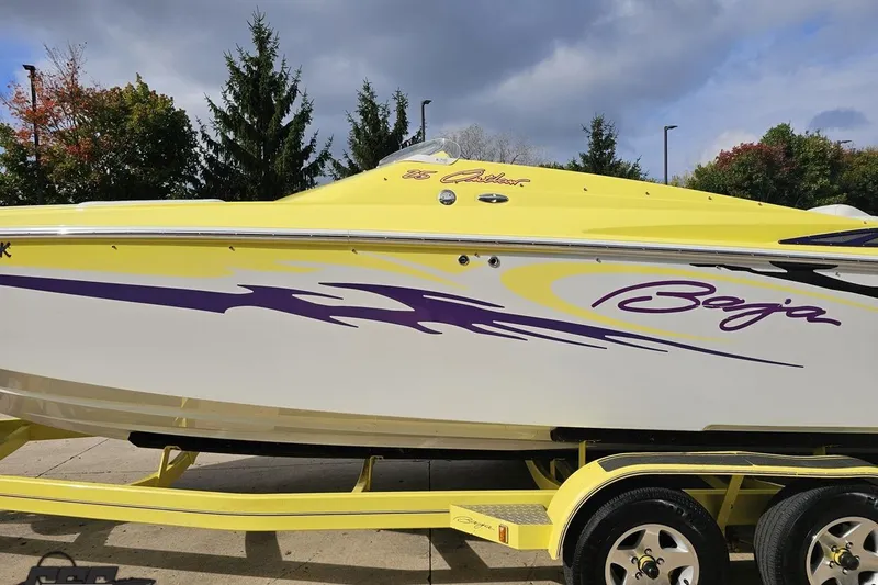 Slide: The Image of 2005 Baja 25 Outlaw speedboat with vibrant yellow and purple graphics on a trailer. - 33