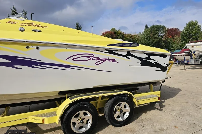Slide: The Image of 2005 Baja 25 Outlaw boat with vibrant yellow and purple graphics on a trailer. - 34