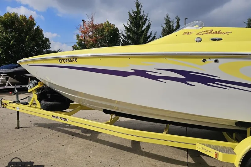 Slide: The Image of 2005 Baja 25 Outlaw speedboat on trailer, yellow with purple graphics, parked outdoors. - 35