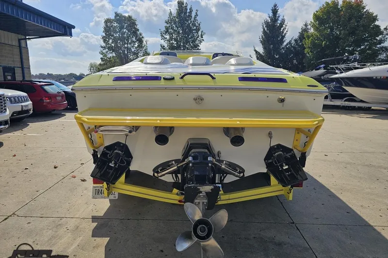 Slide: The Image of 2005 Baja 25 Outlaw boat, rear view, yellow and white, parked outdoors. - 44