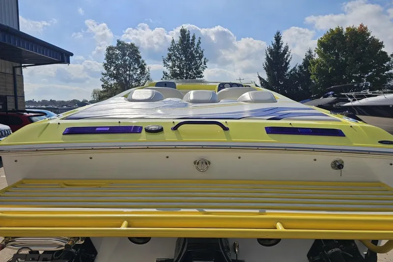 Slide: The Image of 2005 Baja 25 Outlaw boat, yellow and white, parked outdoors under a blue sky. - 51