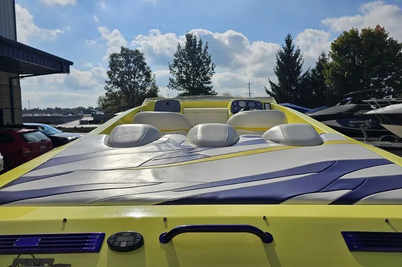 Slide: The Image of 2005 Baja 25 Outlaw boat with vibrant yellow and purple design, parked outdoors. - 52