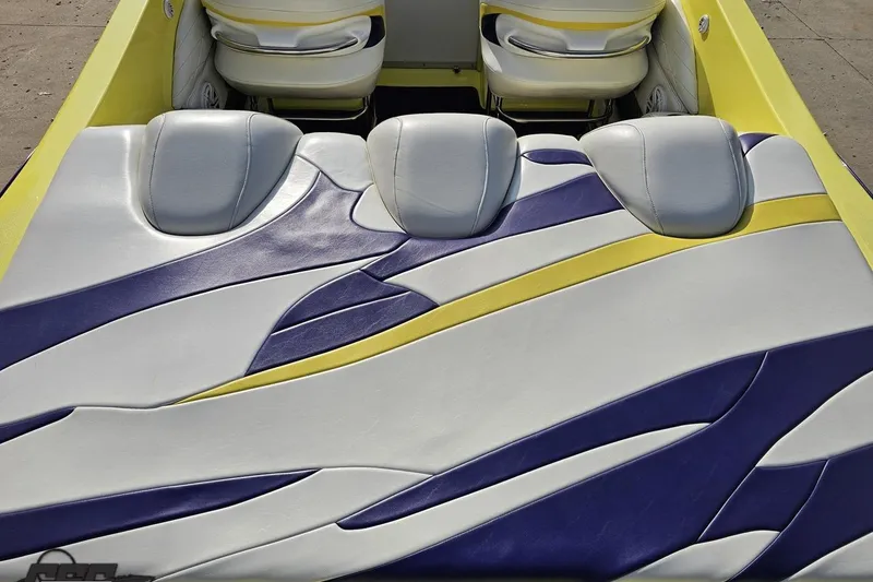 Slide: The Image of 2005 Baja 25 Outlaw boat interior with vibrant yellow, purple, and white upholstery design. - 54